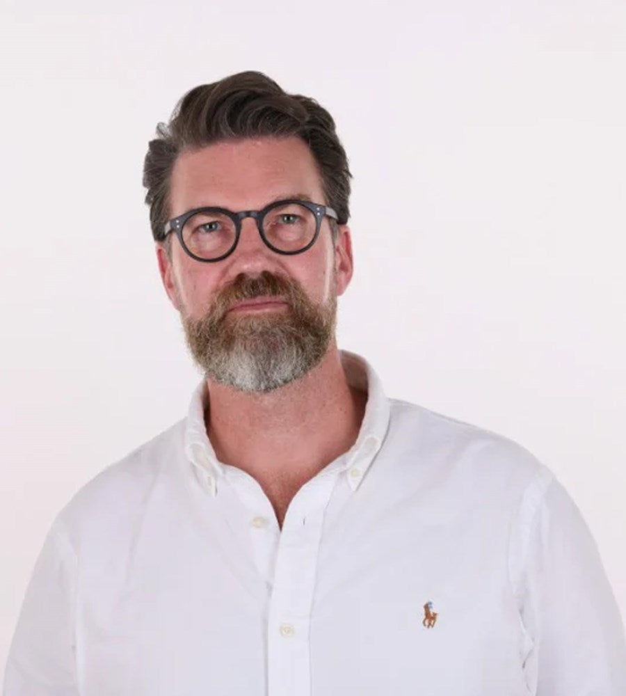 Man wearing glasses and a white shirt with a logo on a white background