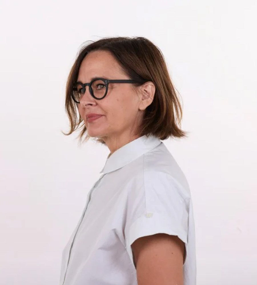 Woman wearing a white shirt and glasses on a plain background