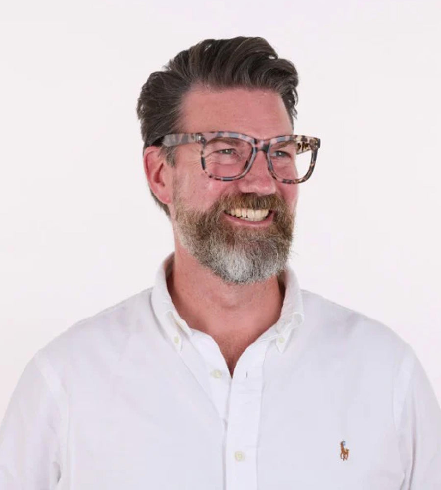 Man wearing glasses and a white shirt with a logo on a white background