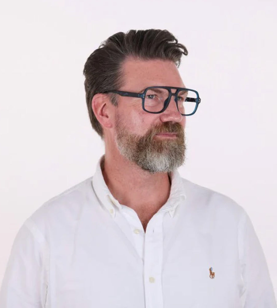 Man wearing glasses and a white shirt with a logo on a white background