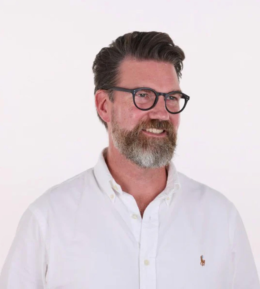 Man wearing glasses and a white shirt with a logo on a white background