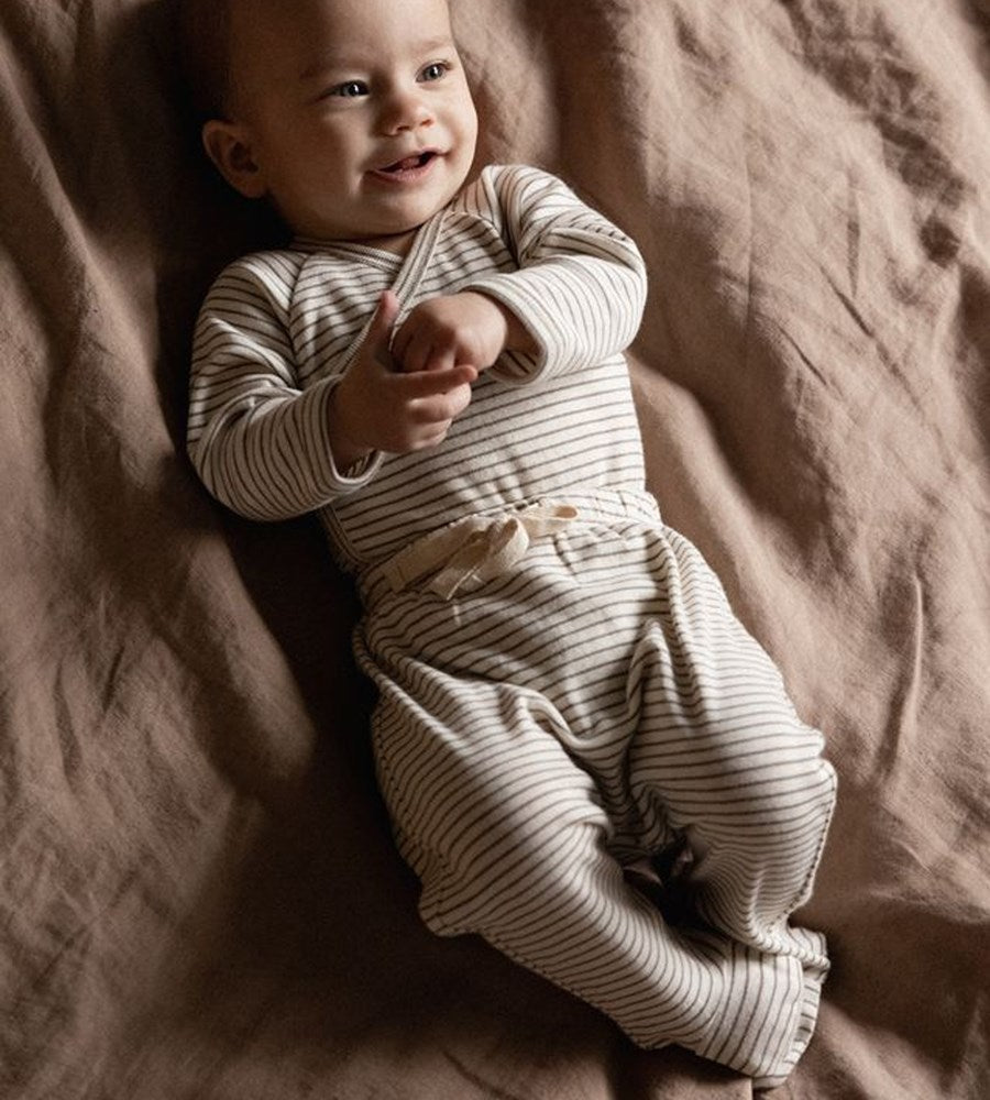 Baby in a striped outfit lying on a soft surface