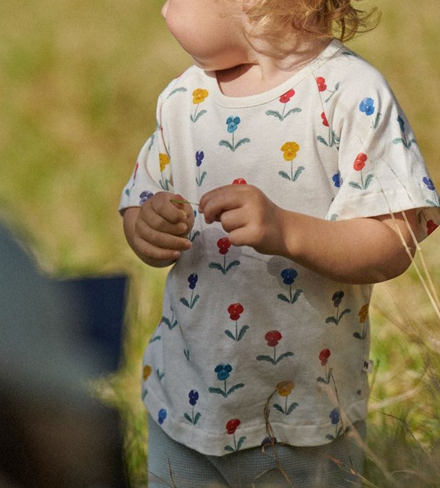 Child wearing a white shirt with colorful floral patterns in a natural setting
