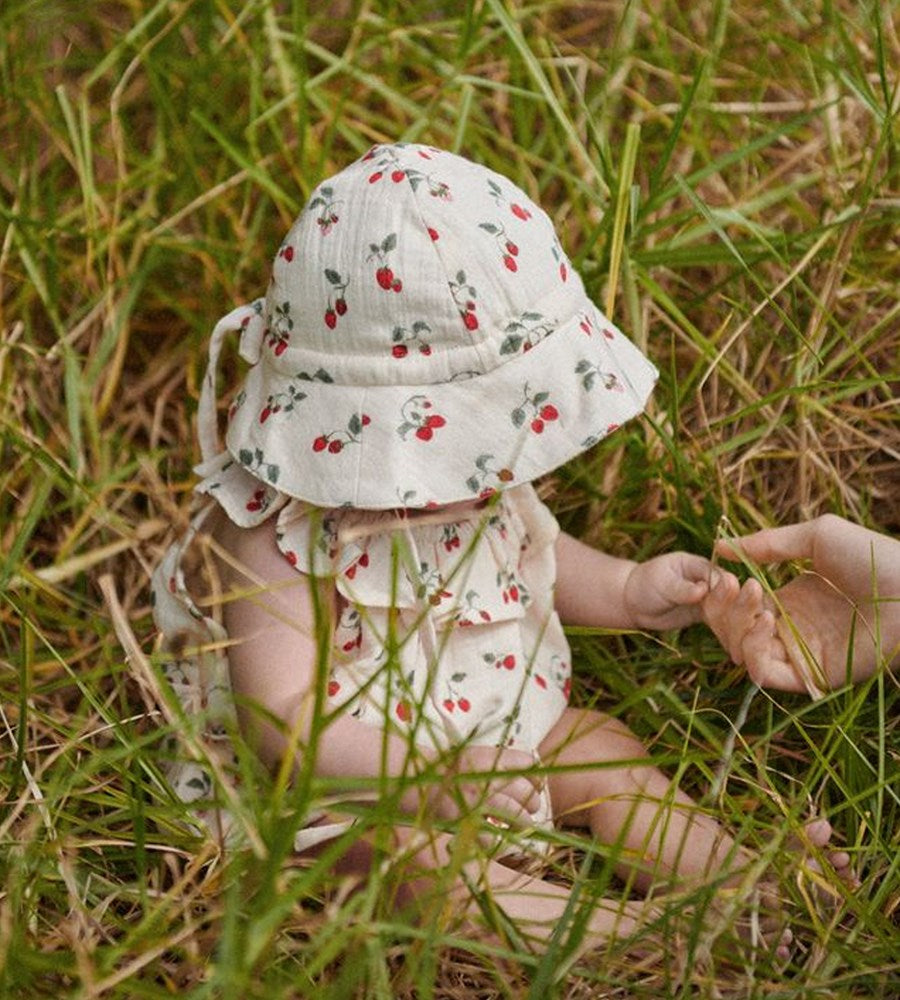 Baby in a floral hat and outfit sitting in grass