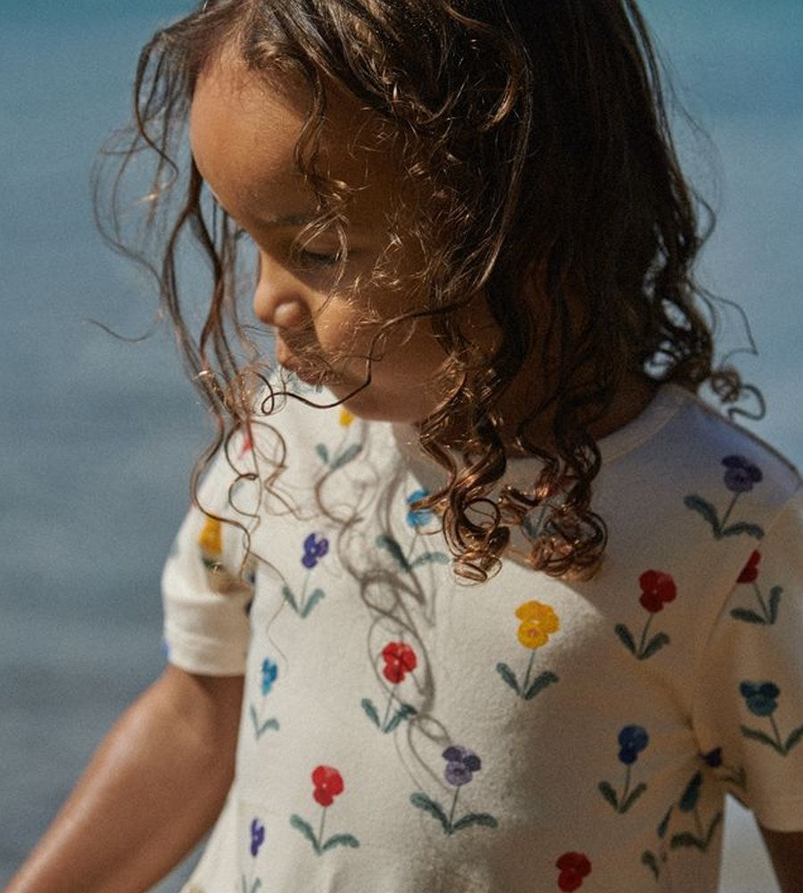 Child wearing a white shirt with colorful floral patterns against a blurred natural background