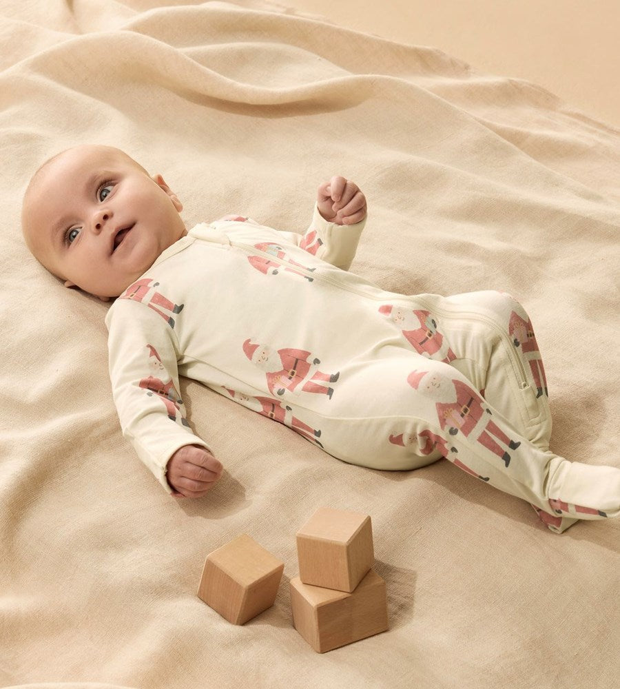 Baby lying on a beige blanket with wooden blocks nearby