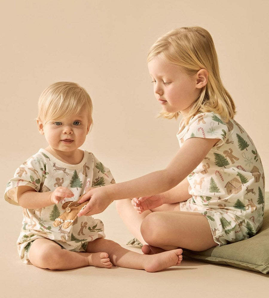 Two children wearing matching pajamas with a forest design on a beige background
