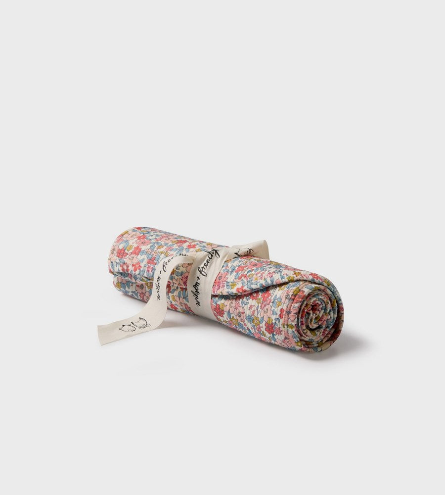 Rolled-up floral-patterned mat with a brand label on a white background