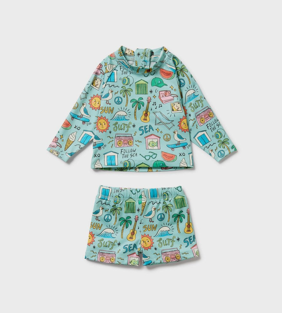Children's swim set with long-sleeve rash guard and shorts featuring a beach-themed pattern on a light gray background.
