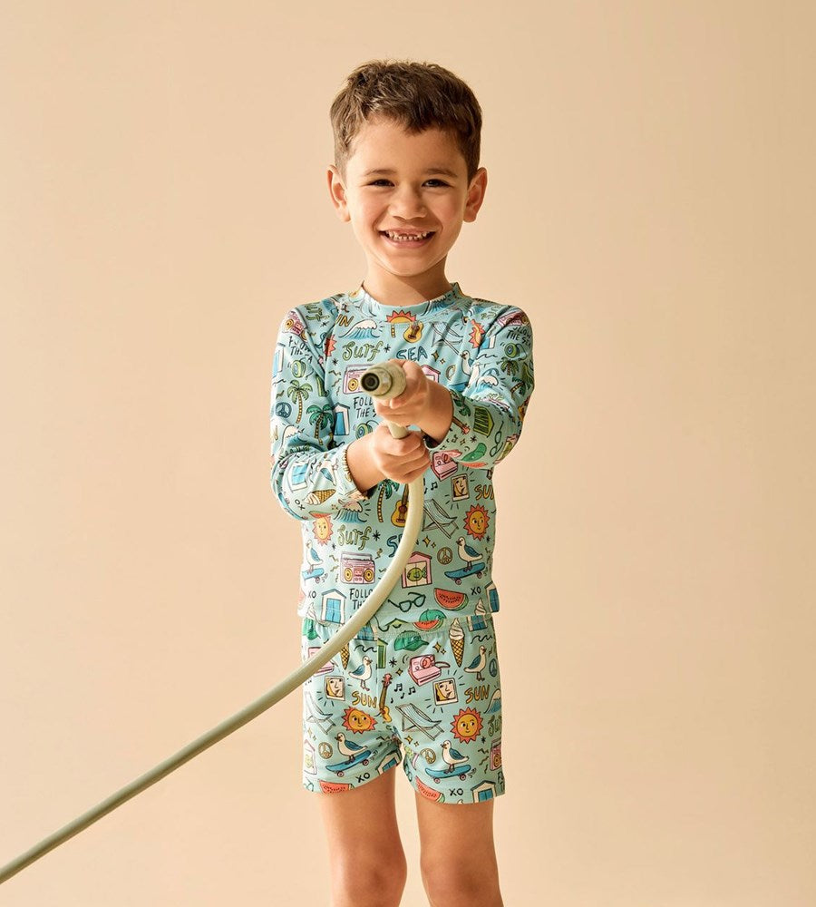Child wearing a colorful swim outfit with a pattern of animals and holding a toy.