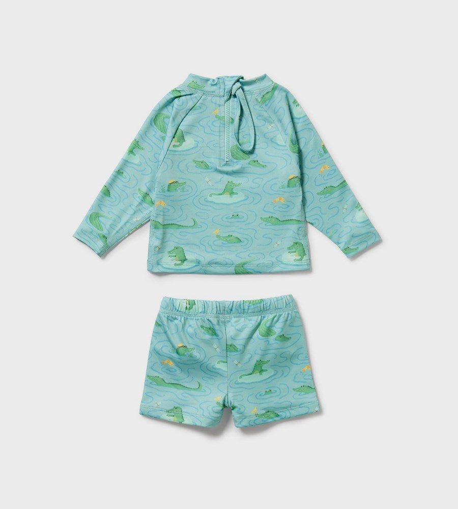 Children's turquoise rash guard with alligator pattern and matching shorts on a light gray background