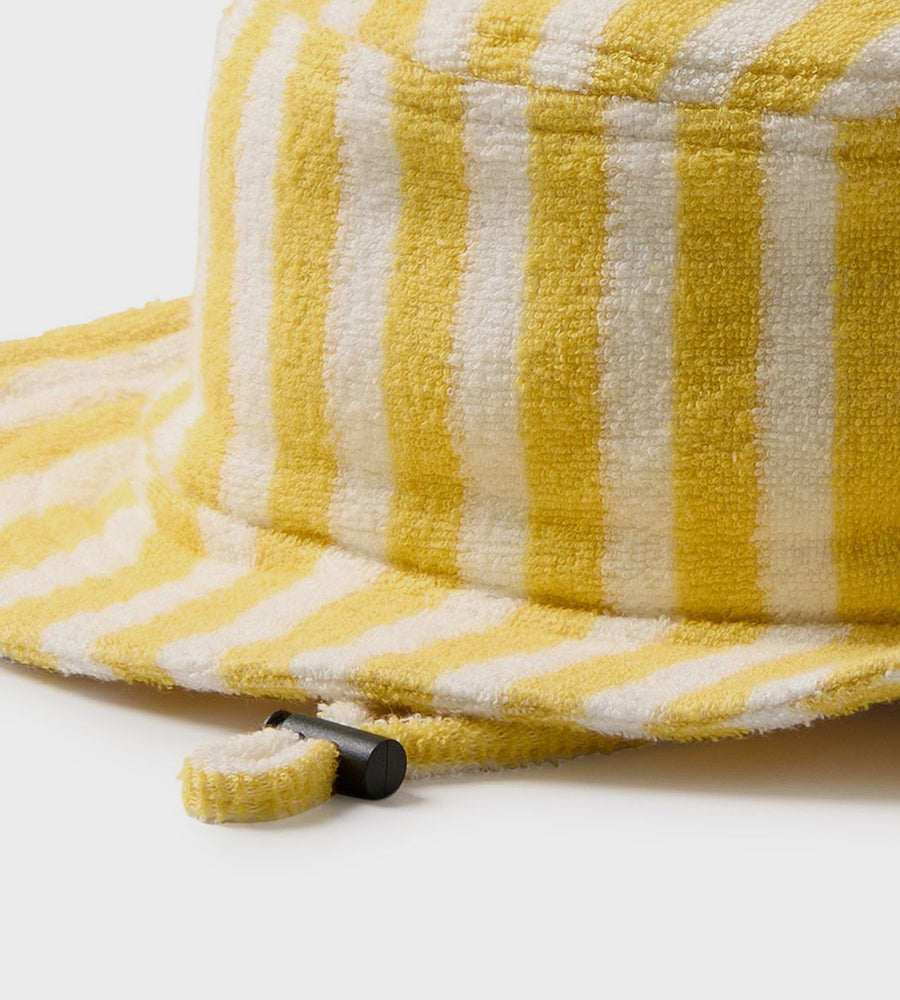 Yellow and white striped towel with a black clip on a light gray background
