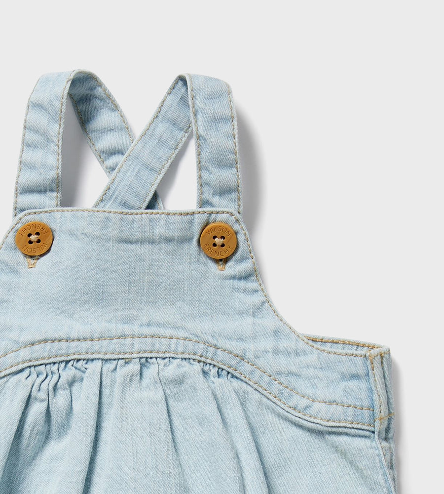 Light blue denim overalls with brown buttons on a light gray background