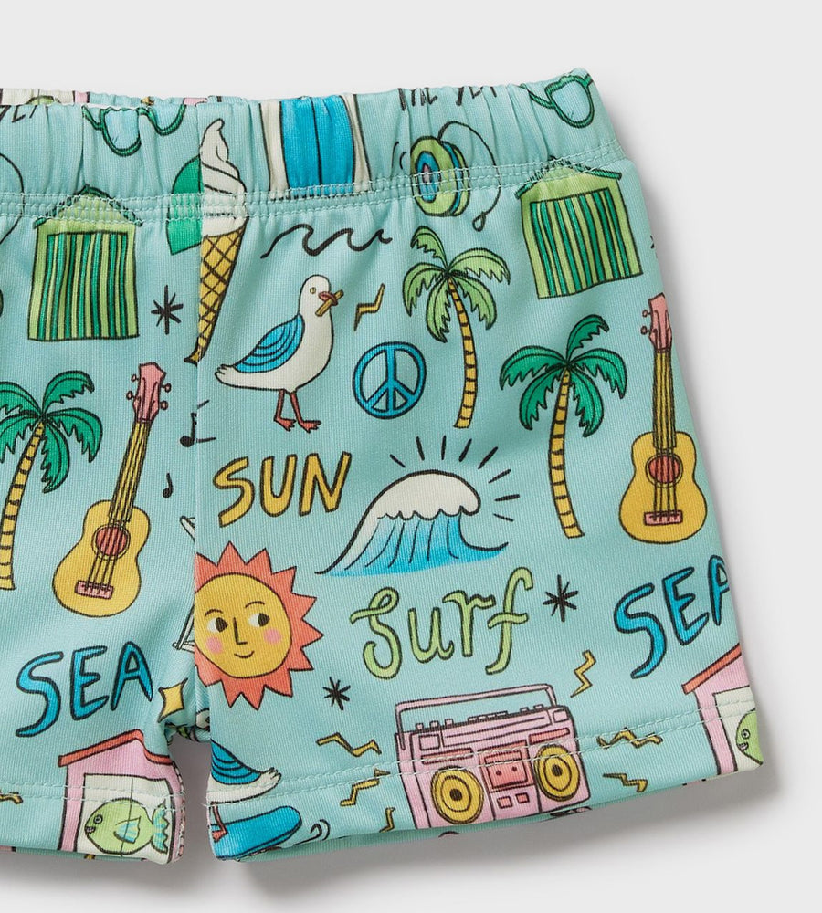 Children's swim shorts with beach-themed graphics on a light blue background